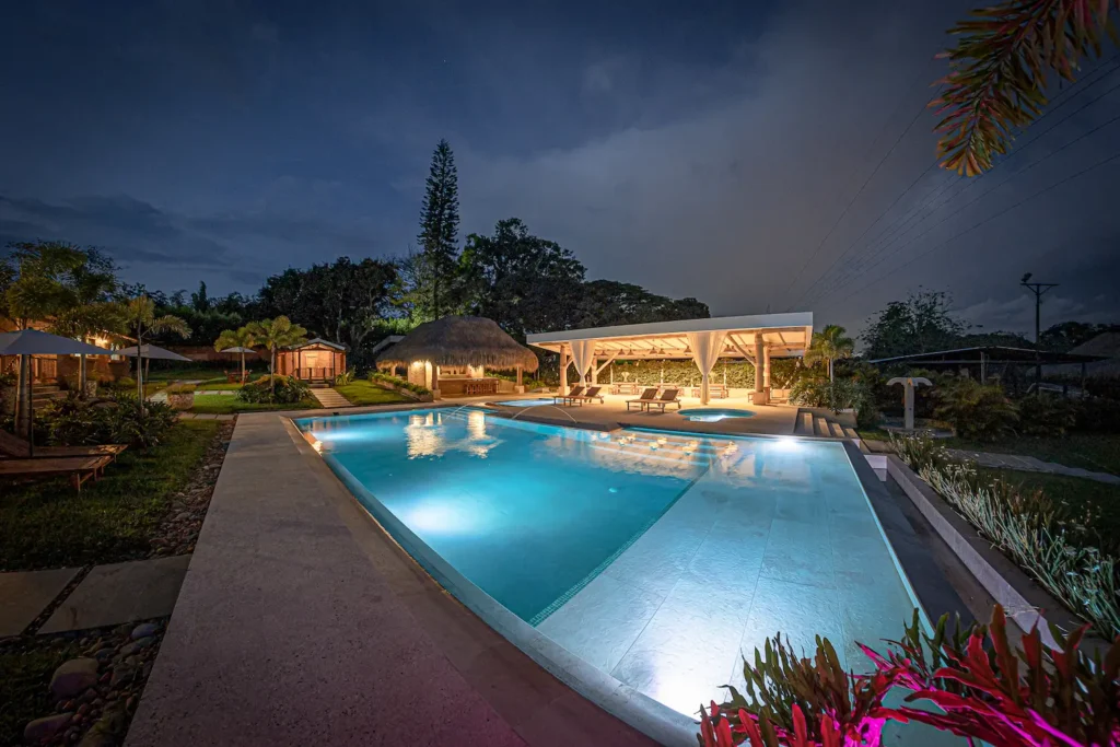 Piscina de noche, con restaurante al fondo